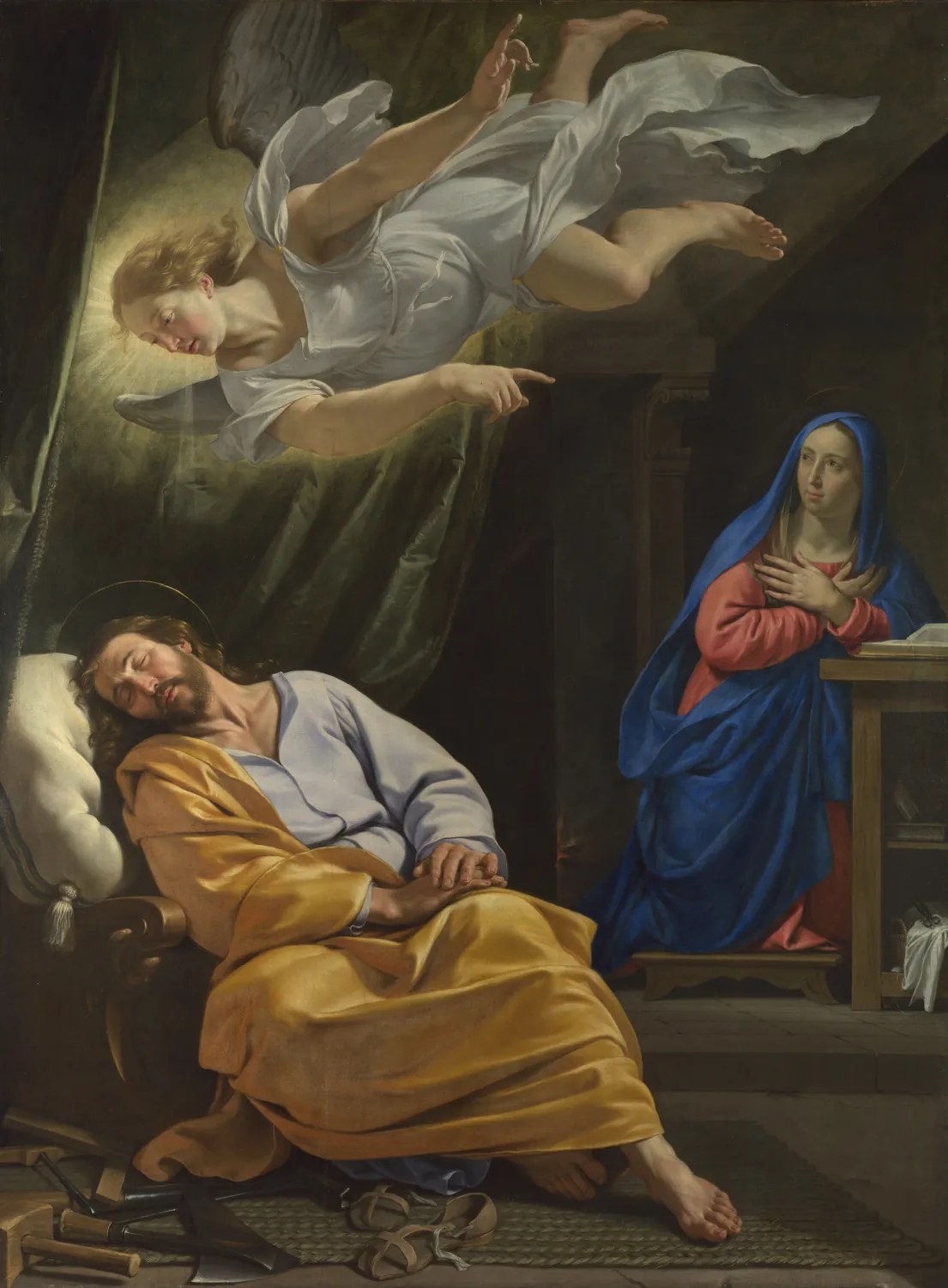 A man in a yellow robe sleeps in a chair. An angel glows in the air above him and points. A woman in blue stands at a small table on the right.