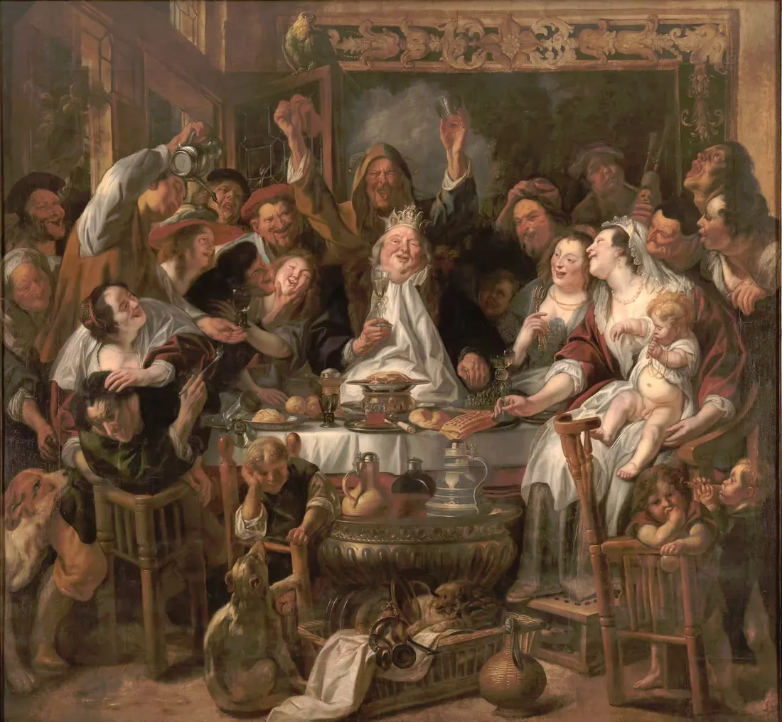 A crowded table at a feast, a bearded man in a paper crown lifting a glass while the others cheer.
